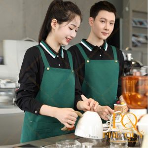 Nhân viên quán cà phê mặc áo cổ bẻ tay dài màu đen phối tạp dề yếm xanh lá