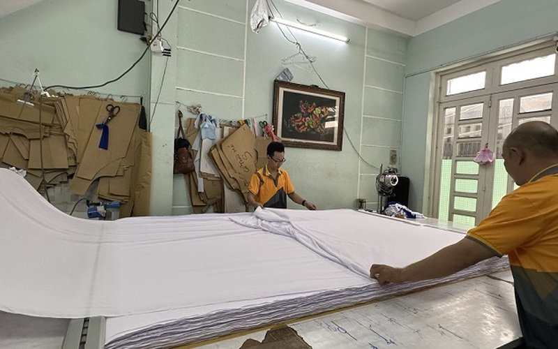 Thợ may đang tiến hành kiểm tra kích thước, màu sắc vải sơ mi trước khi tiến hành sản xuất